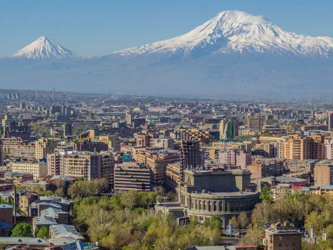 Ереван хотын барилгууд, ногоорч буй модод, ард нь цастай оройтой Их, Бага Арарат уул, цэлмэг тэнгэр