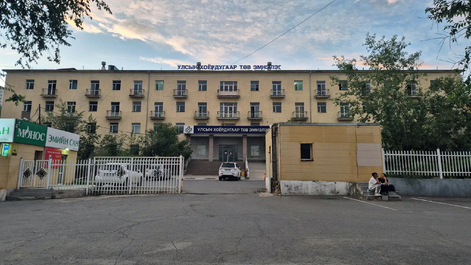 Үүлтэй тэнгэрийн доорх шар өнгийн дөрвөн давхар эмнэлгийн барилга, дээрээ «Улсын хоёрдугаар төв эмнэлэг» бичигтэй, урд талын зогсоол